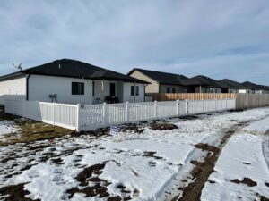 A newly installed residential white vinyl fence standing in a snowy landscape by Rio Fence Co. in Lincoln, NE.