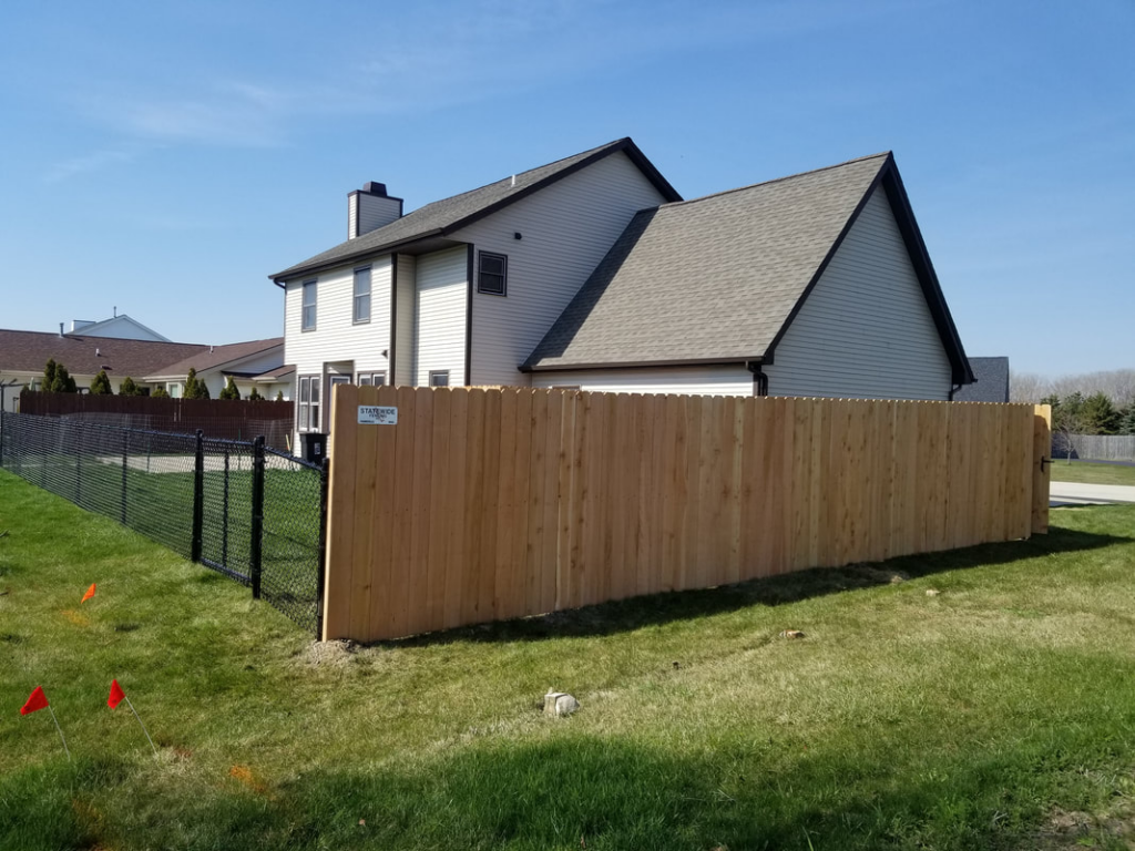 A newly installed residential wood and chain-link fence by Statewide Fencing, Inc. in Franksville, WI