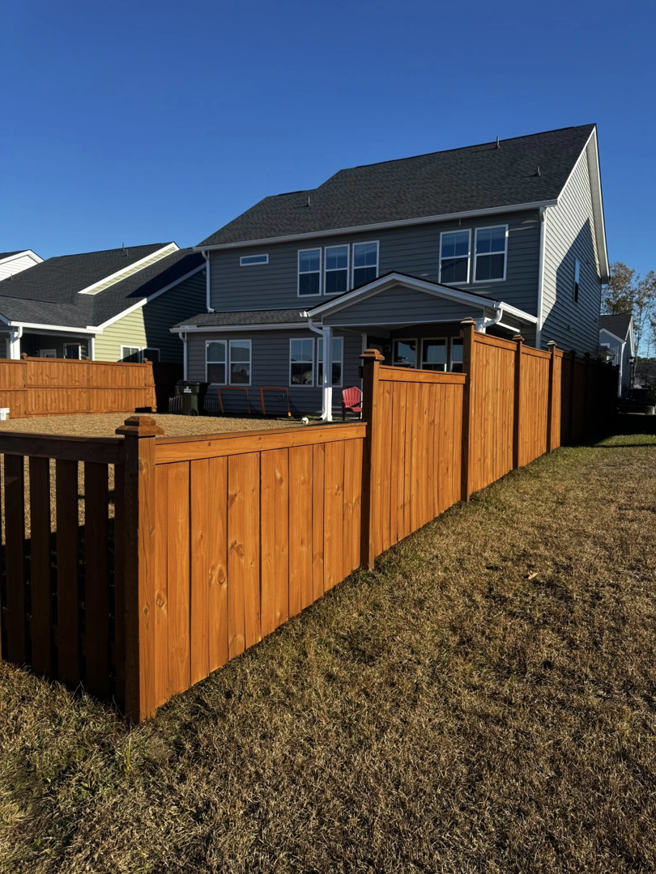 A residential backyard showcasing a newly installed wood fence with both privacy and picket sections by Stain and Go in Summerville, SC.