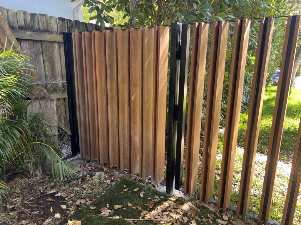 A residential wood and black metal fence with a gate providing privacy, installed by ARE FENCE LLC in Miami, FL.