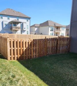 A completed residential wood picket fence in a backyard by Hotshot Fencing and Gates in Kansas City, MO.