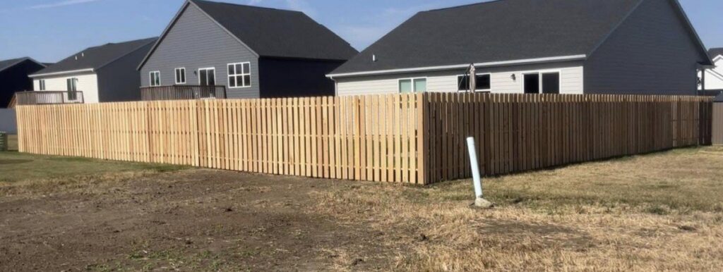 A new wooden picket fence installed around a residential property by The GateKeeper Perimeter Fence & Automated Security in Sioux Falls, SD