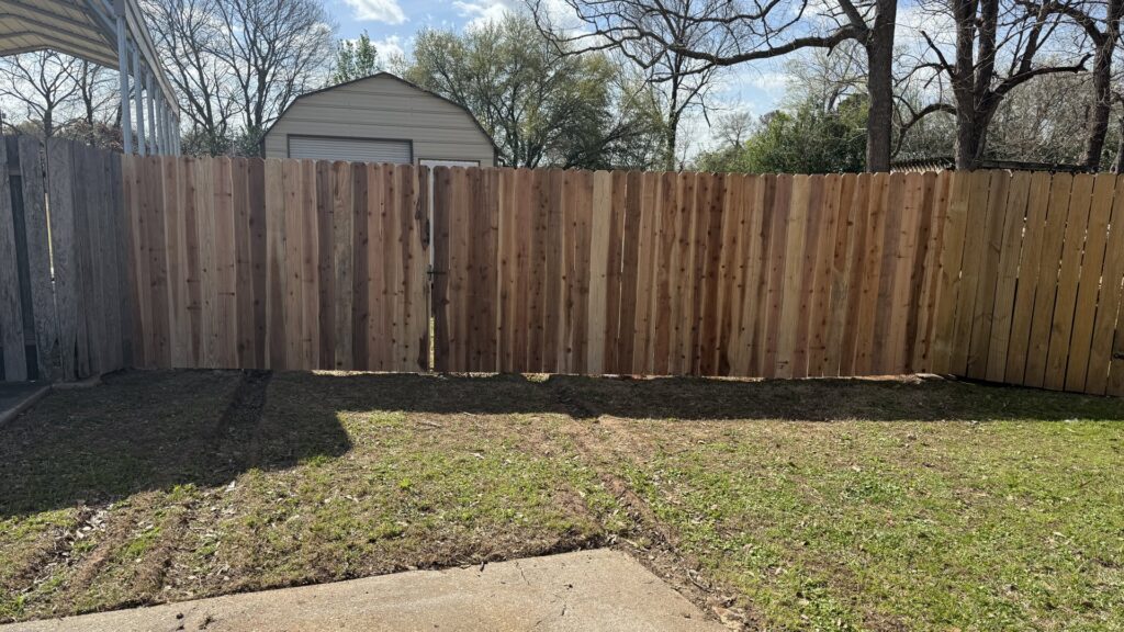 A new wood privacy fence with a gate installed in a residential backyard by C & M Affordable Fence, LLC in Haughton, LA