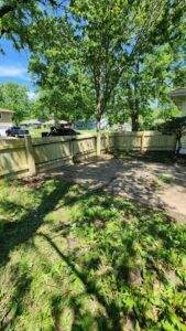 A newly installed wood privacy fence with a gate in a residential backyard, completed by Hotshot Fencing and Gates in Kansas City, MO.