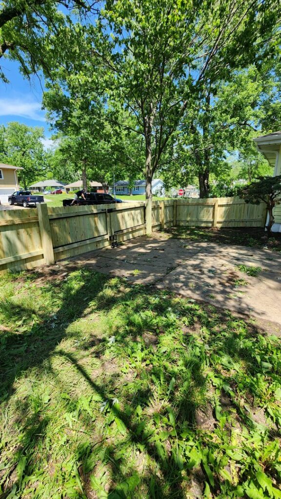 A newly installed wood privacy fence with a gate in a residential backyard, completed by Hotshot Fencing and Gates in Kansas City, MO.