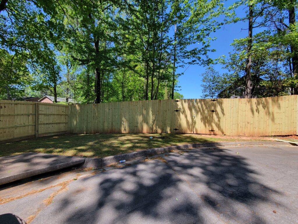 A long, newly installed wood privacy fence in a residential backyard by Hawk Fences LLC in Johns Creek, GA.