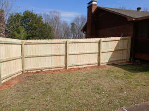 A new wood privacy fence installed alongside a residential home by Top Rail Fence Birmingham, AL