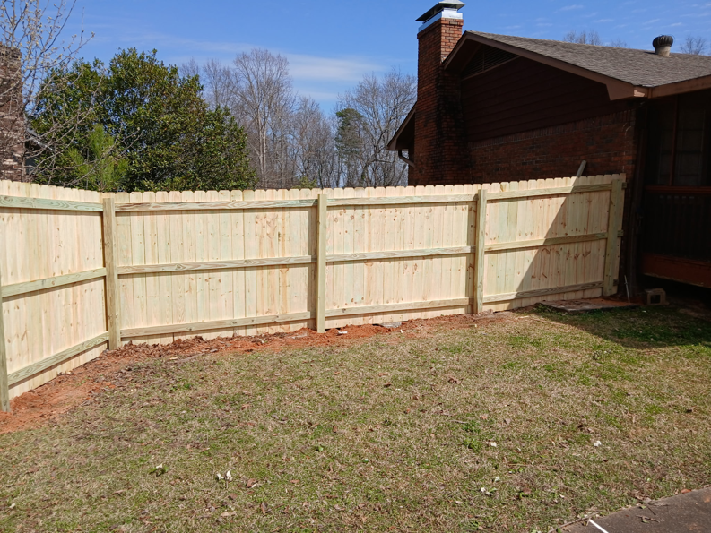 A new wood privacy fence installed alongside a residential home by Top Rail Fence Birmingham, AL