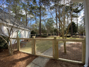 A residential wood and wire mesh fence with a gate installed by Renegade Fencing, LLC in Jacksonville, NC.