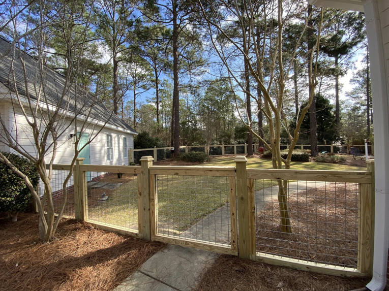 A residential wood and wire mesh fence with a gate installed by Renegade Fencing, LLC in Jacksonville, NC.