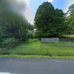 Residential property featuring a wooden privacy fence and a rustic split-rail fence, showcasing work by Wayside Fences in Brattleboro, VT.