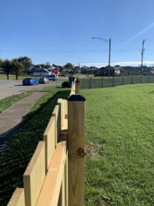 A newly installed residential wooden privacy fence with decorative post caps along a street by Roark Fencing in Lexington, KY