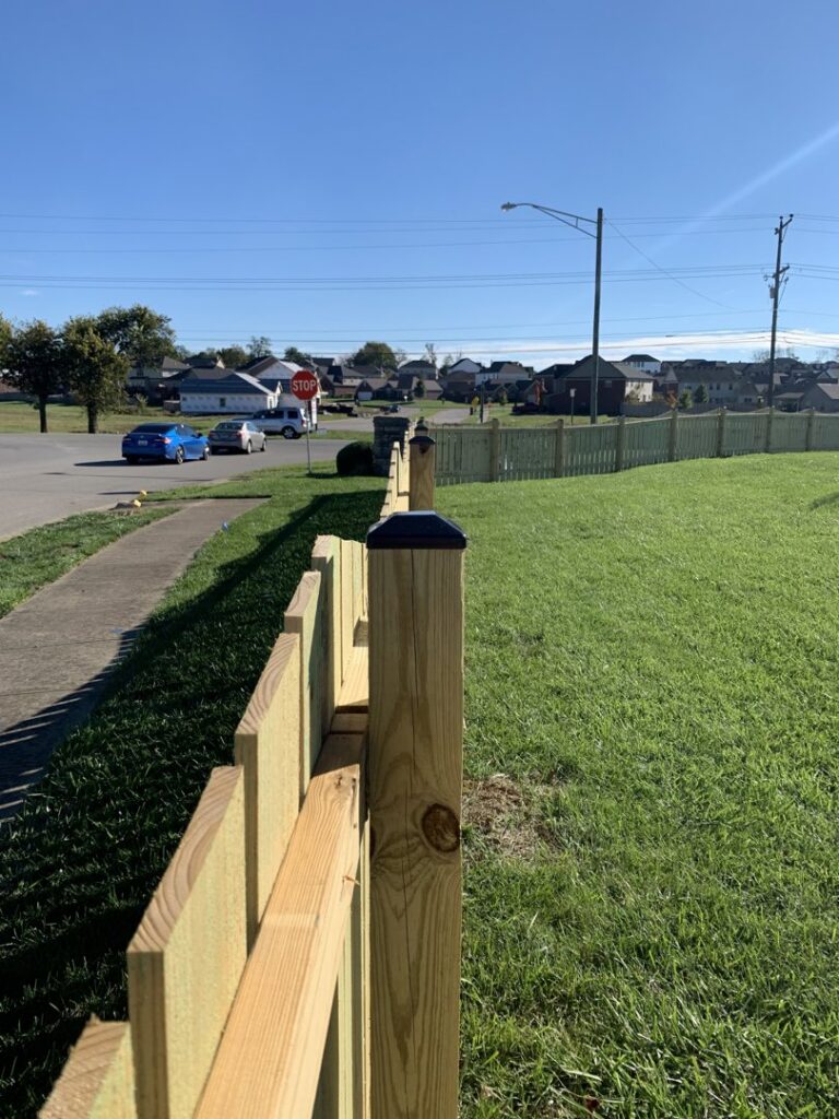 A newly installed residential wooden privacy fence with decorative post caps along a street by Roark Fencing in Lexington, KY