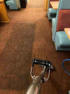 A carpet cleaning machine cleaning a brown carpet in a restaurant for First Choice Janitorial Services in Vancouver, WA.