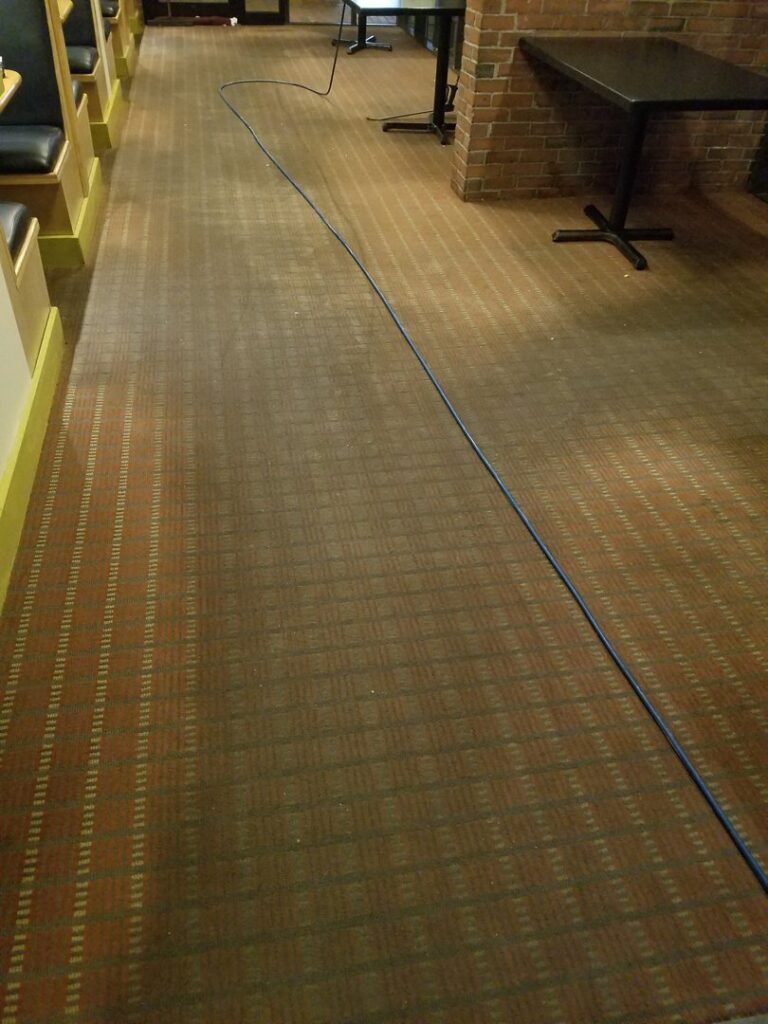 Restaurant carpet cleaning in progress with a long blue hose by Keith's Cleaning Service in Auburn, ME