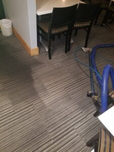Restaurant carpet cleaning in progress with a cleaning wand, showing a clean and dirty section, by Keith's Cleaning Service in Auburn, ME