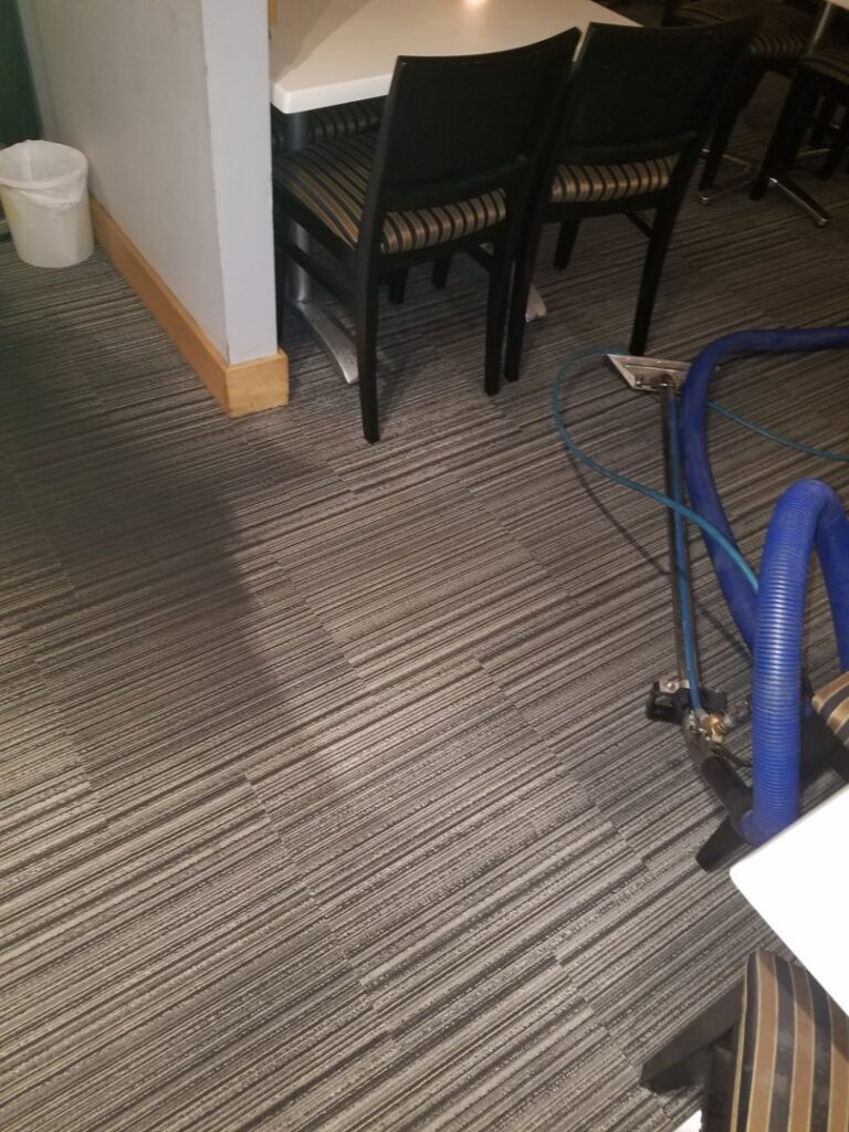Restaurant carpet cleaning in progress with a cleaning wand, showing a clean and dirty section, by Keith's Cleaning Service in Auburn, ME