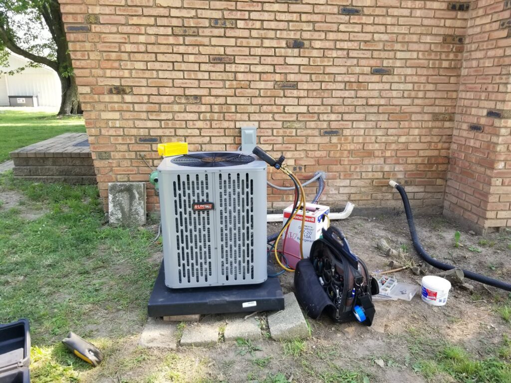 A Rheem outdoor AC condenser unit being serviced by Debbie's Heating and Cooling in South Bend, IN.