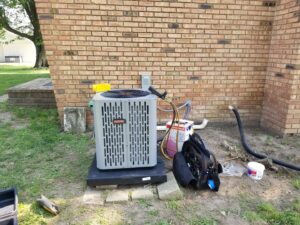 A Rheem outdoor AC condenser unit being serviced by Debbie's Heating and Cooling in South Bend, IN.