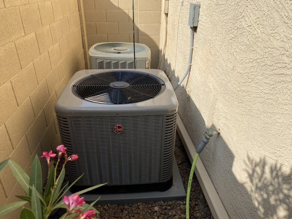 A Rheem AC unit installed in a narrow space next to a house by Kings of AC, LLC in Queen Creek, AZ.