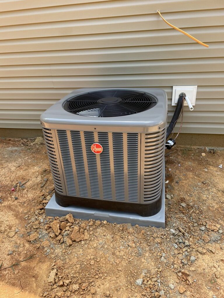A new Rheem outdoor AC unit installed next to a house by MTZ Heating and Air Conditioning in Charlotte, NC.