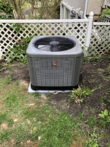 An outdoor Rheem air conditioning unit installed in a residential yard by Garrison City HVACR in Dover, NH
