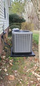 An HVAC technician servicing a Rheem outdoor AC unit with gauges connected by MTZ Heating and Air Conditioning in Charlotte, NC.