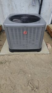 An outdoor Rheem air conditioning unit installed on a concrete pad by The HVAC Doc in Rock Springs, WY