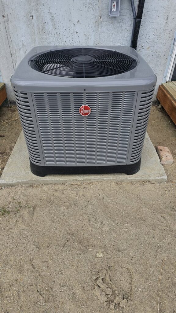 An outdoor Rheem air conditioning unit installed on a concrete pad by The HVAC Doc in Rock Springs, WY