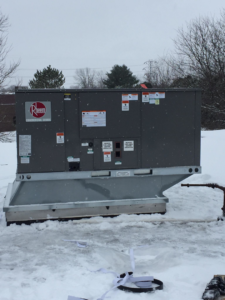 A large Rheem commercial HVAC unit sitting in the snow, ready for installation or service by Spencer Heating & Air Conditioning in Norcross, GA.
