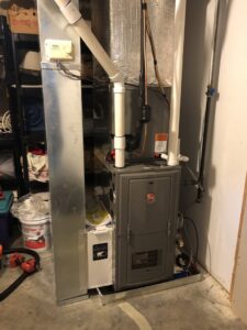 A Rheem furnace and air handler unit with ductwork installed in a utility area by Garrison City HVACR in Dover, NH