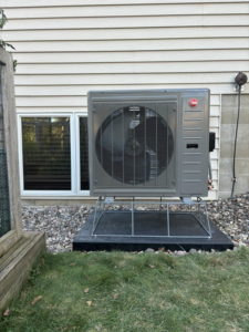 A newly installed Rheem heat pump outdoor unit next to a house by BRY Heat and Air in Elgin, MN