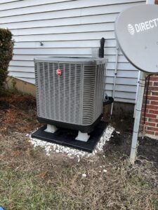 An outdoor Rheem HVAC condenser unit installed next to a residential home by GrinHouse HVACR in La Grange, KY.