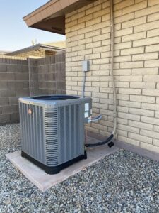 A Rheem outdoor AC unit installed next to a brick house by Kings of AC, LLC in Queen Creek, AZ.