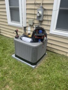 A Rheem outdoor air conditioning unit with tools on top, indicating service by Hendrix Heating & Air in Newport News, VA.