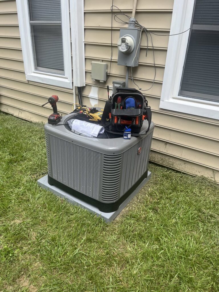 A Rheem outdoor air conditioning unit with tools on top, indicating service by Hendrix Heating & Air in Newport News, VA.