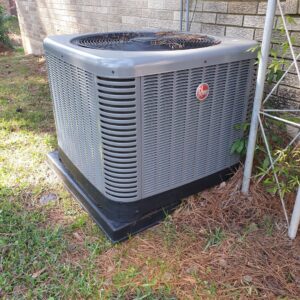 A Rheem outdoor HVAC condenser unit installed next to a residential brick house by Home Shield Heating and Air in Shreveport, LA.