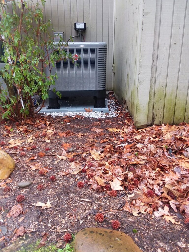 A Rheem outdoor HVAC condenser unit installed next to a home during the fall season by Appliance Doctor, Inc. in Annapolis, MD.