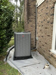 A Rheem outdoor HVAC unit professionally installed next to a brick house by Underwood Heating and Air Conditioning in Phenix City, AL