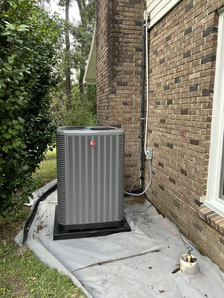 A Rheem outdoor HVAC unit professionally installed next to a brick house by Underwood Heating and Air Conditioning in Phenix City, AL