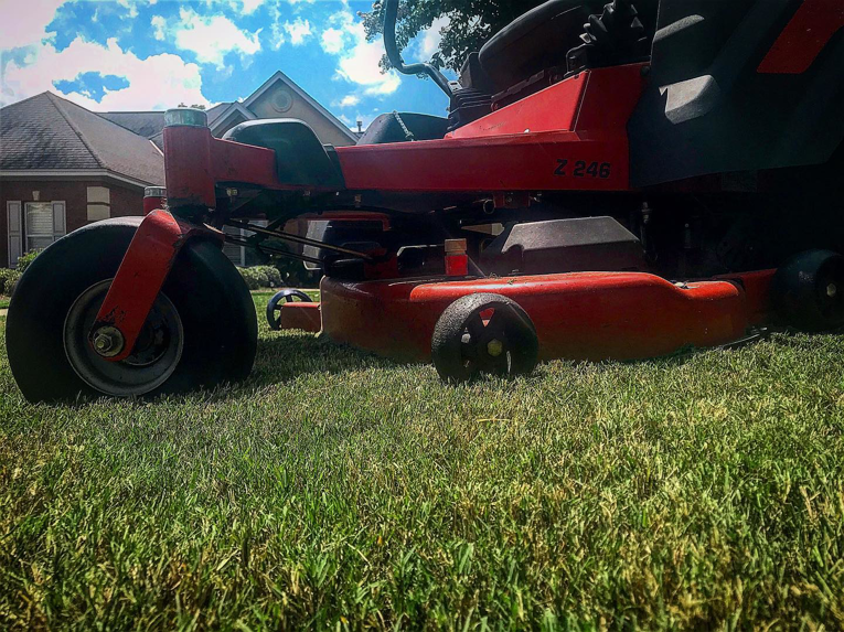 A red riding lawn mower on a well-maintained residential lawn by Thorn Lawn Service in Montgomery, AL.