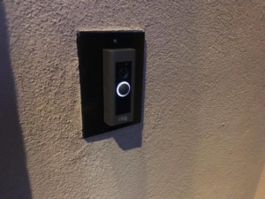 A Ring smart doorbell professionally installed on a textured wall by Lundell Electrical Services in Mesa, AZ.