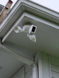 A Ring floodlight camera installed under the eaves of a house by ABS Electrical Services in Rogers, AR.