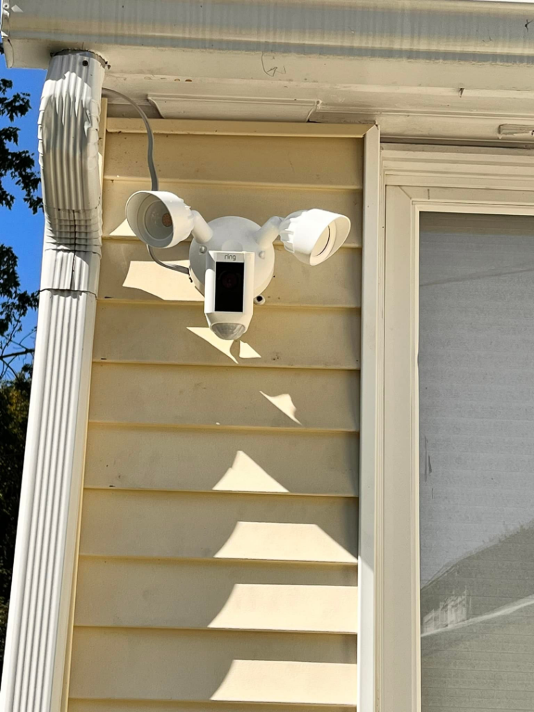 A Ring floodlight camera professionally installed on house siding by Fuse Electrical LLC in Rochester, NY
