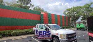 A Rivers Pest Control Service, Inc. truck parked in front of a large building covered in a fumigation tent in Jacksonville, FL
