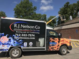 An R.J. Nelson Co service truck with a boom lift extended for commercial HVAC work in Council Bluffs, IA.