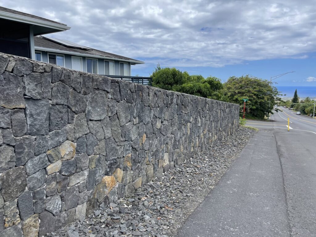 A durable roadside lava rockwall constructed by Fence, Gates and Rockwalls, providing property boundary in Kailua-Kona, HI