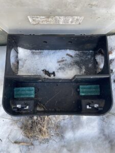 An open rodent bait station with green bait blocks in the snow, used for winter rodent control by Pike Creek Exterminating in Kenosha, WI.