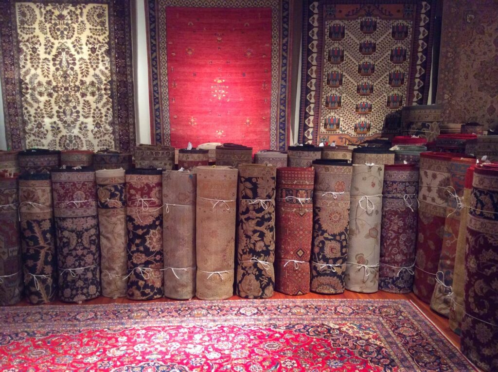 A showroom displaying numerous rolled and hanging oriental rugs, showcasing the selection at Brandon Oriental Rugs in Furlong, PA.
