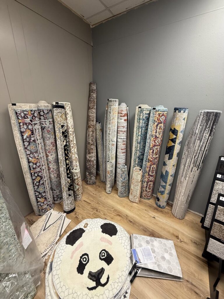 A display of various rolled area rugs and smaller rugs at Symbols Flooring in Soldotna, AK